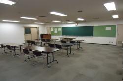 前方の黒板に向けて机やイスが並んでいる研修室の写真